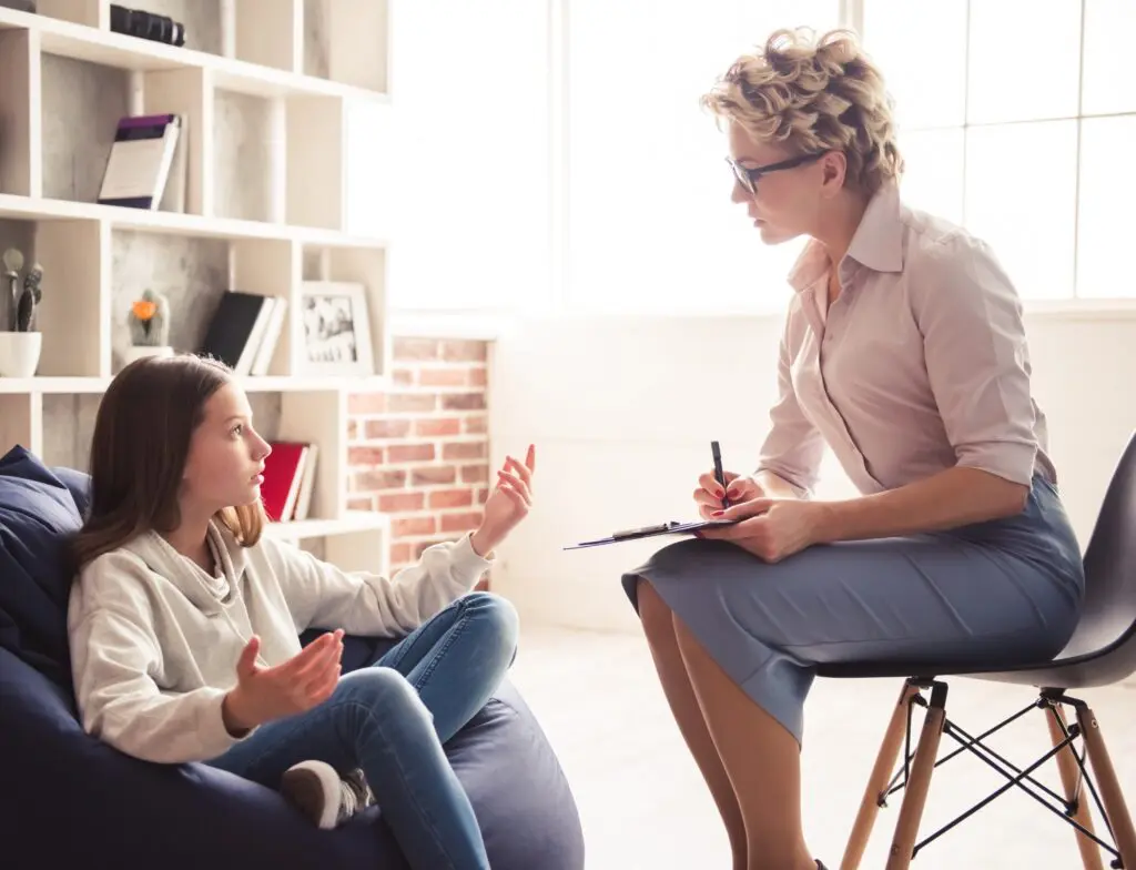 Teenage girl is talking to the psychotherapist while sitting in doctor's office