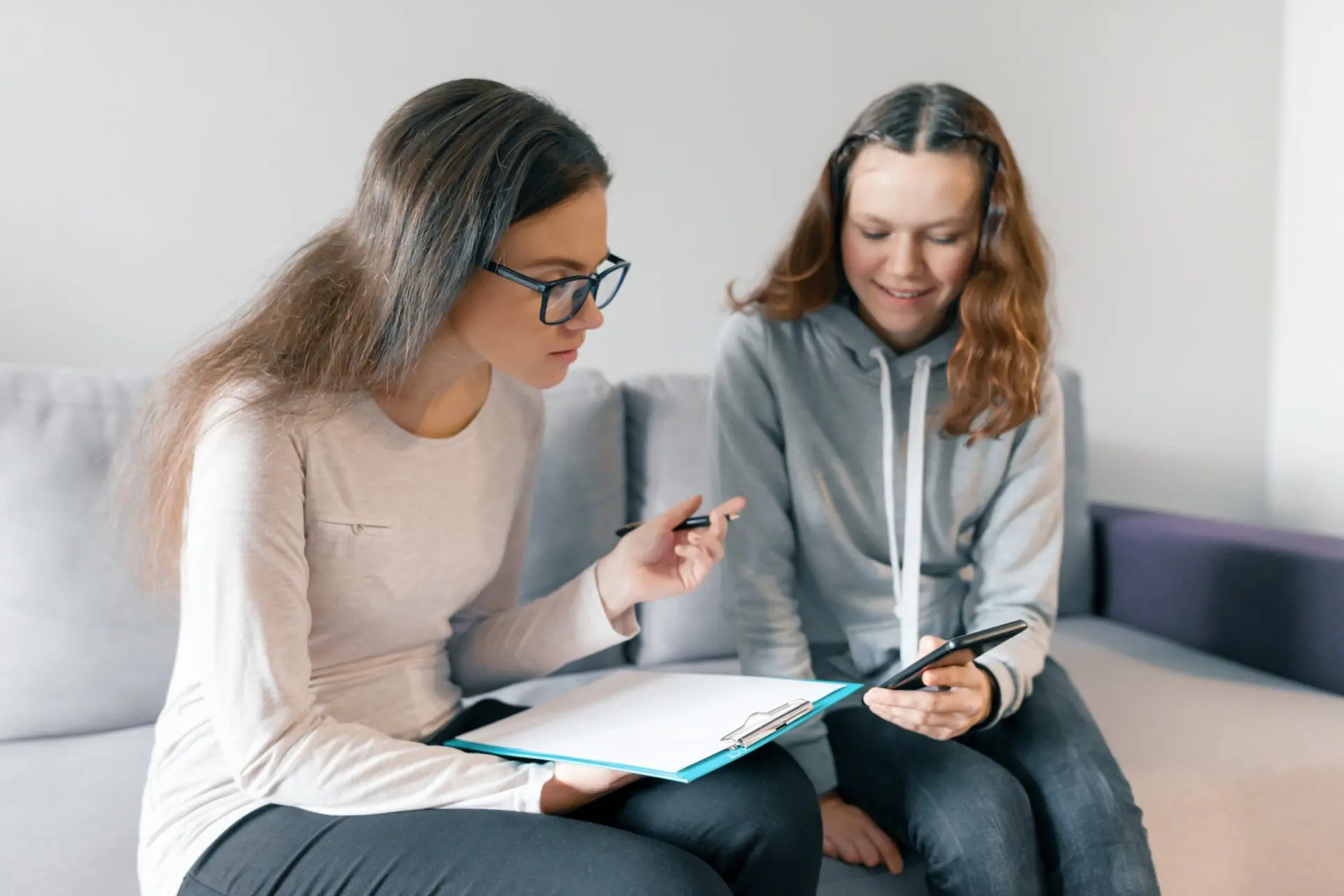 Young woman professional psychotherapist talking with teen girl in office. Mental health of child in adolescence. Young woman professional psychotherapist talking with teen girl in office